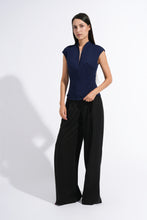 Load image into Gallery viewer, A woman modeling a navy blue sleeveless top with a split neckline and black wide-leg trousers, standing against a plain white studio background.