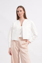 Load image into Gallery viewer, Woman wearing a white blouse and beige pants on a white background

