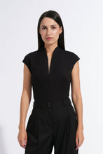 Load image into Gallery viewer, A woman modeling a black sleeveless jumpsuit with a split neckline, high-waisted wide-leg pants, and a matching waist belt, photographed against a plain white studio background.

