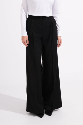 Person wearing black wide-leg pants and a white top on a white background