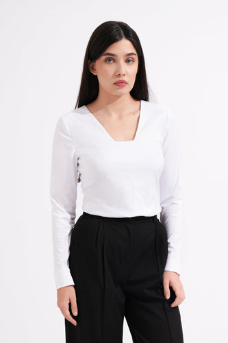 Woman wearing a white long-sleeve top and black pants on a white background
